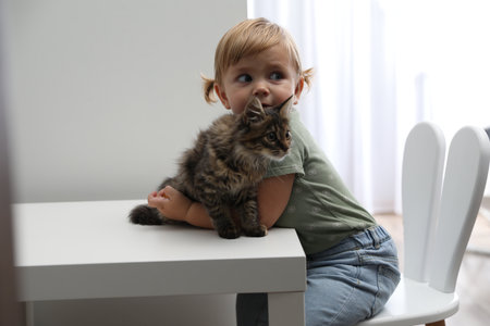 Cute little child with adorable pet at white table in roomの写真素材