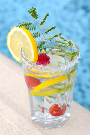 Delicious refreshing lemonade with raspberries near swimming pool, closeupの写真素材