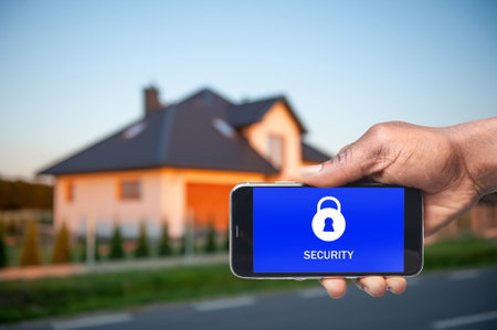 home security system. African American man with smartphone near his house outdoors, closeupの写真素材