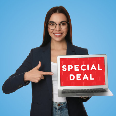 special deal. Young woman pointing at laptop on light blue backgroundの写真素材