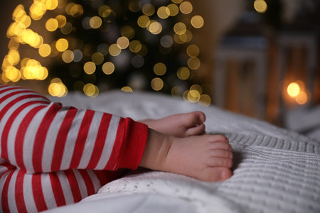 Baby in Christmas pajamas sleeping on bed indoors, closeup