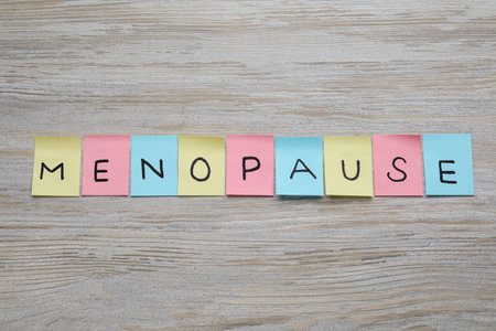 Colorful paper notes with word Menopause on wooden table, flat layの写真素材