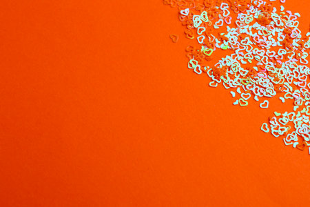 Shiny bright heart shaped glitter on coral background. Space for textの写真素材