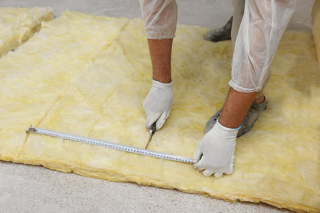 Worker measuring and cutting insulation material indoors, closeupの写真素材