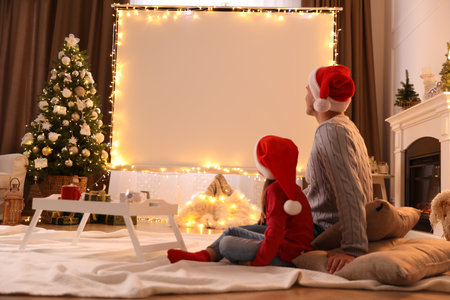 Father and daughter watching movie using video projector at home. Cozy Christmas atmosphereの写真素材