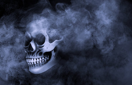 Scary skull emerging from smoke in darknessの写真素材