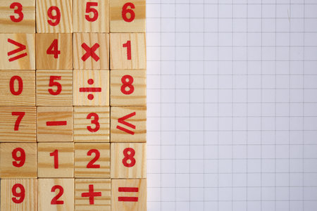Wooden cubes with mathematical symbols and numbers on sheet of grid paper, flat lay. Space for textの写真素材