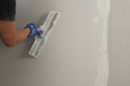 Professional worker plastering wall with putty knife, closeupの写真素材