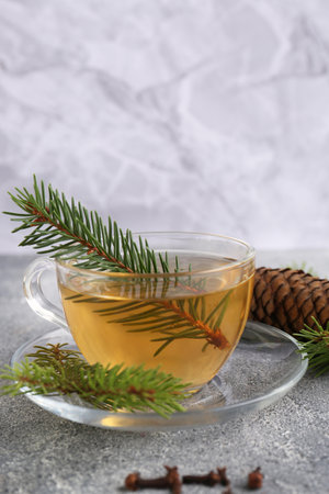 Cup with delicious immunity boosting tea and fir on gray tableの写真素材