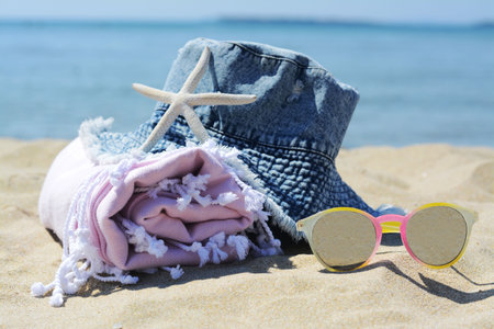 Stylish beach accessories on sand near the seaの写真素材
