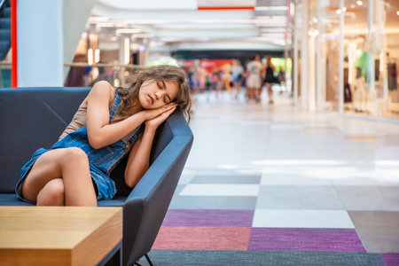 Tired teenage girl sleeping on sofa in shopping mallの写真素材
