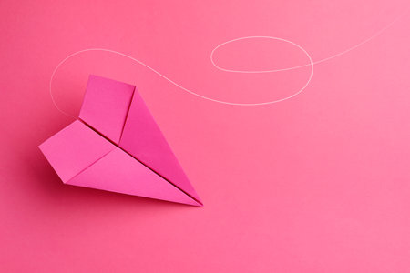 Handmade paper plane on pink background, top view. Space for textの写真素材