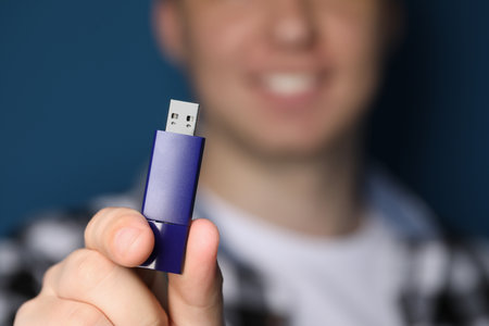 Man with usb flash drive on blue background, closeup. Space for textの写真素材