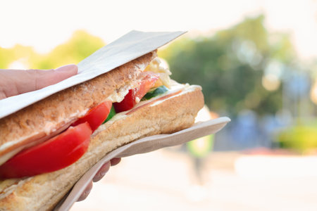 Woman holding tasty sandwich with vegetables outdoors, closeup and space for text. street foodの写真素材