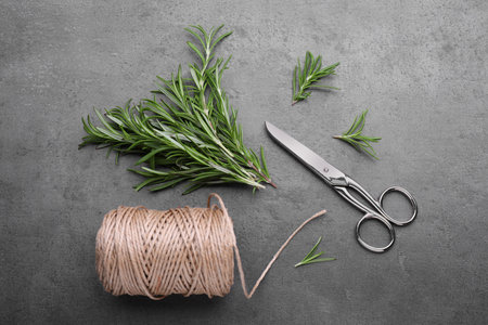 Sprigs of rosemary, scissors and twine on black background, flat layの写真素材