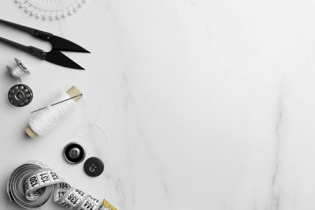 Threads and other sewing supplies on white marble table, flat lay. Space for textの写真素材