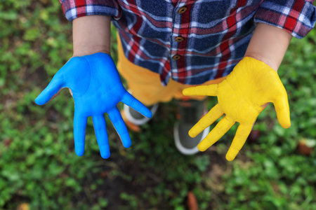 Little boy with hands painted in Ukrainian flag colors outdoors, top view. love Ukraine conceptの写真素材