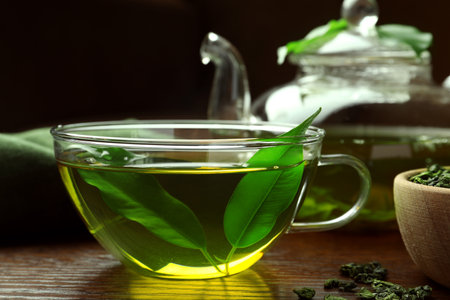 Fresh green tea in glass cup with leaves on wooden table, closeupの写真素材