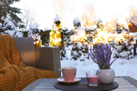 Candle, potted flowers and cup of hot drink on coffee table outdoors. Cozy winterの写真素材