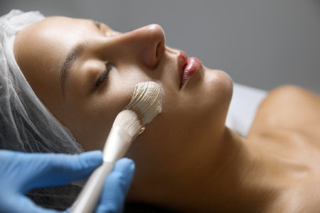 Cosmetologist applying mask on client's face in spa salon, closeupの写真素材