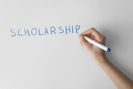 Woman writing word SCHOLARSHIP on white paper, closeupの写真素材