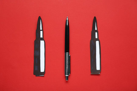information warfare concept. Paper bullets and pen on red background, flat layの写真素材