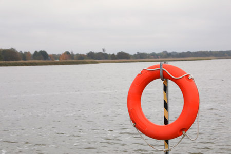 Orange lifebuoy hanging near sea outdoors, space for text. real estate