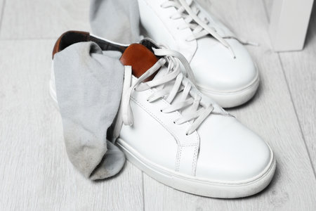 Sneakers with dirty socks on white wooden floor indoorsの写真素材