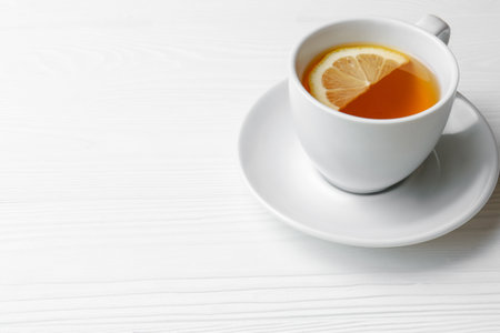 Cup with delicious immunity boosting tea and lemon on white wooden table, space for textの写真素材
