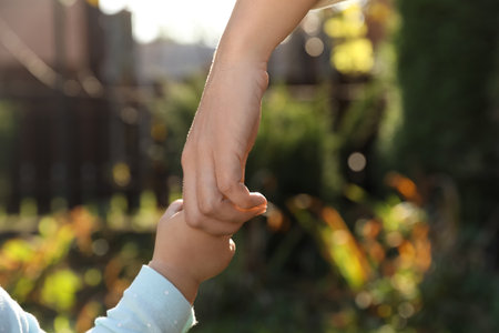 Daughter holding mother's hand outdoors, closeup viewの写真素材