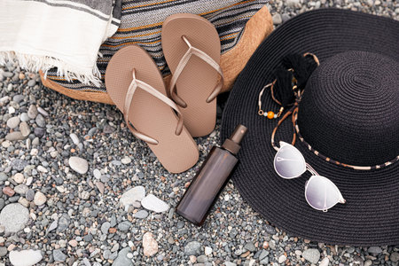 Set of different stylish beach accessories on pebble seashore, above view