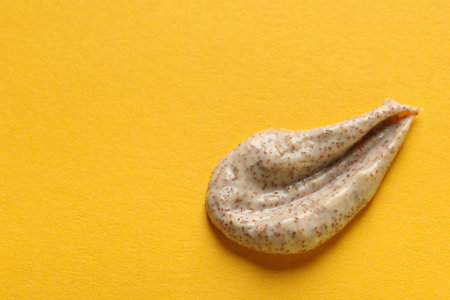 Sample of scrub on orange background, top view. Space for text