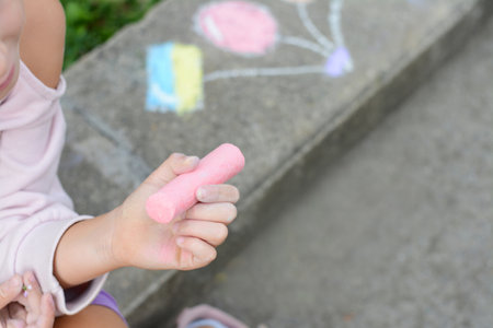 Little child chalk piece sitting on curb outdoors, closeup. Space for textの写真素材