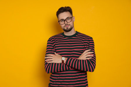 Handsome man in striped sweatshirt and eyeglasses on yellow backgroundの写真素材