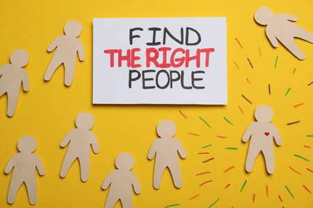 Find the right people. Human paper figure with drawn heart among others without it on yellow background, flat layの写真素材