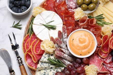 Wooden plate with different delicious snacks on white marble table, flat layの写真素材