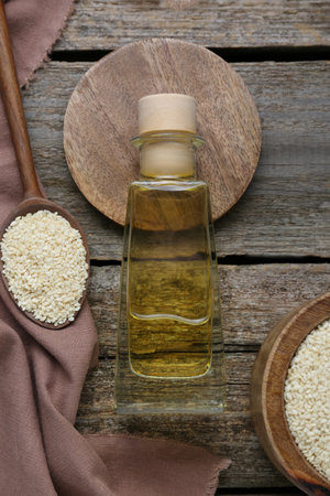 Bottle of organic sesame oil and seeds on wooden table, flat layの写真素材
