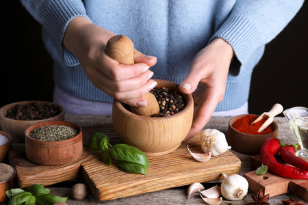Woman grinding peppercorns at wooden table, closeupの写真素材