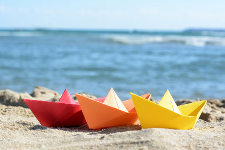 Three paper boats near sea on sunny dayの写真素材