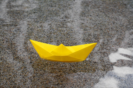 Beautiful yellow paper boat on water outdoorsの写真素材