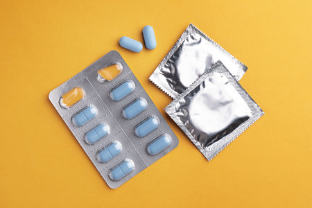 Pills and condoms on orange background, flat lay. Potency problemの写真素材