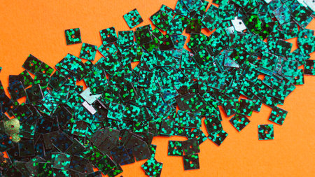Many green sequins on orange background, flat layの写真素材