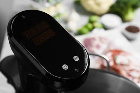 Sous vide cooker in pot on table, closeup. Thermal immersion circulator