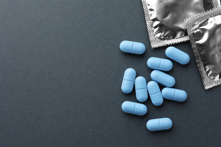 Pills and condoms on dark gray background, flat lay with space for text. Potency problemの写真素材