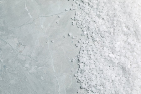 Natural sea salt on light gray marble table, top view. Space for text
