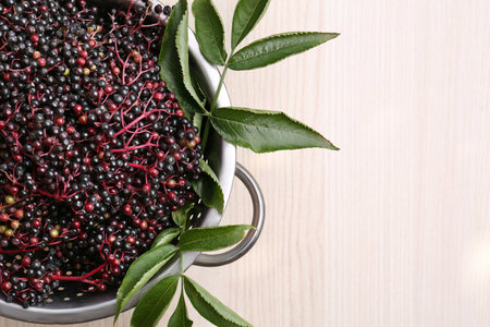 Tasty elderberries (Sambucus) on wooden table, top view. Space for text