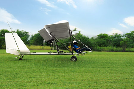 Man in light aircraft on green grass outdoors
