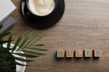 Word Rules made of cubes with letters on wooden table, flat lay