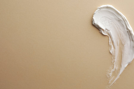 Sample facial cream on beige background, top view. Space for textの写真素材