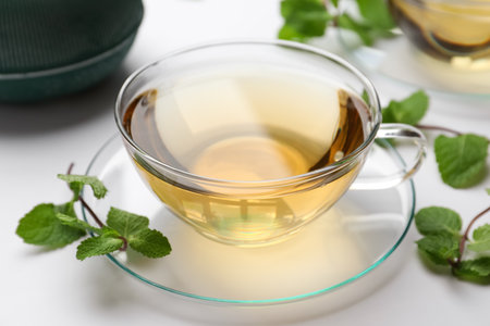 Cup of aromatic herbal tea with mint on white tableの写真素材